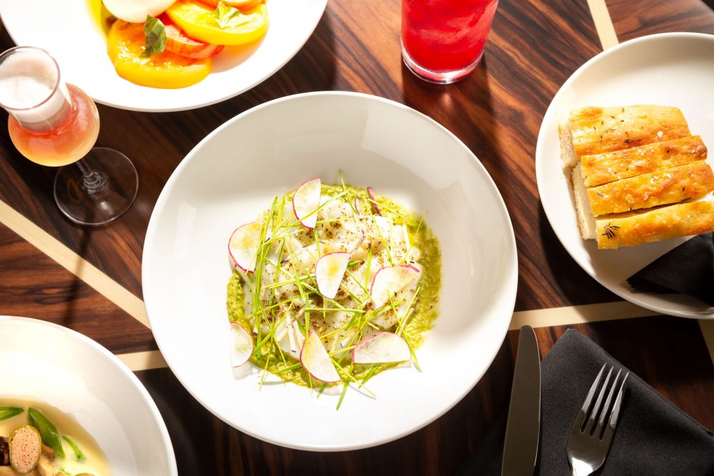 A plate of scallops among other food on a table at Copper & Salt Northwest Kitchen